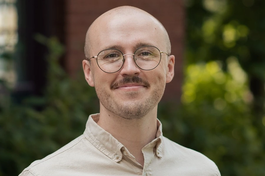 middle aged bald man in cream shirt smiling 